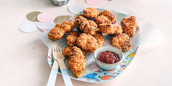 Délicieusement croustillants et prêts en moins d'une heure, des nuggets de poulet sur une assiette avec du ketchup, préparés avec l'appli Cookit Bosch.  