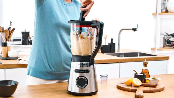 Mujer prepara hummus en la batidora VitaPower Serie 4 con la ayuda de un empujador.