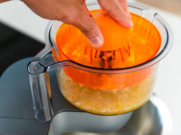 putting oranges into juicer attachment