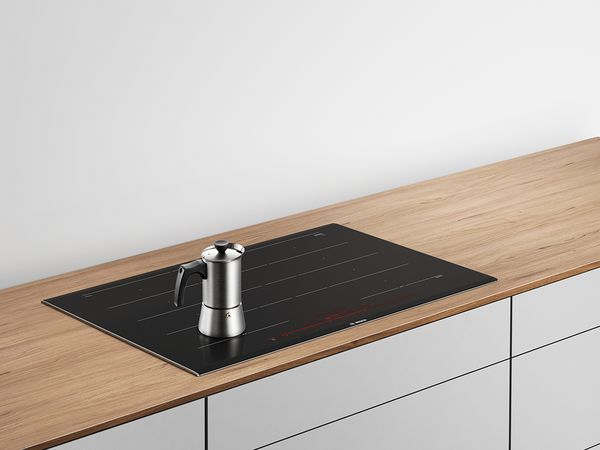 Pro Induction espresso maker on a Bosch hob in a white kitchen.