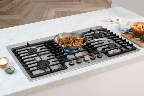 Cooktop with food and pan on middle burner