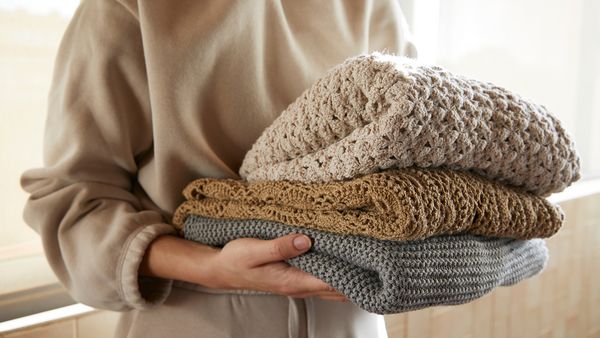 Woman carrying folded jumpers.
