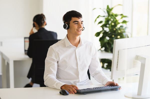 Personne portant des écouteurs travaillant à un bureau dans un bureau moderne.