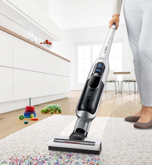 Woman vacuuming up confetti from a high-pile rug with the Athlet.