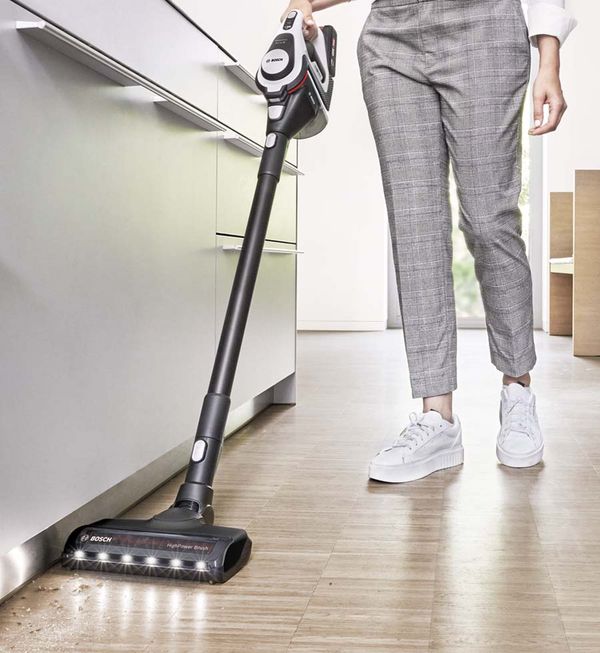 Mulher limpa o chão da cozinha com um aspirador flexível sem fios Unlimited.