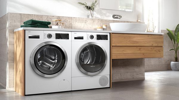 Eine Waschmaschine und ein Trockner nebeneinander in einem modernen Bad.