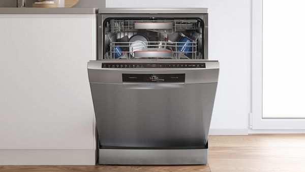 An open built-in dishwasher in a white kitchen.