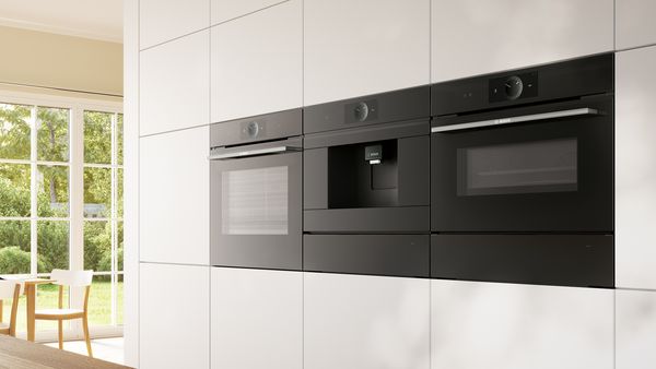 Atractivo horno, cafetera espresso y microondas Bosch integrados en una pared.