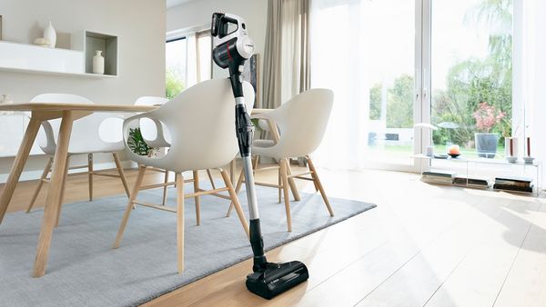 Vacuum cleaner propped up against chair in room