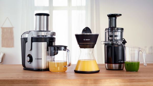 Соковыжималка Bosch стоит на кухонной столешнице со свежеприготовленными соками.
