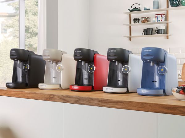 Different colours of the TASSIMO FINESSE coffee machine on a kitchen worktop.