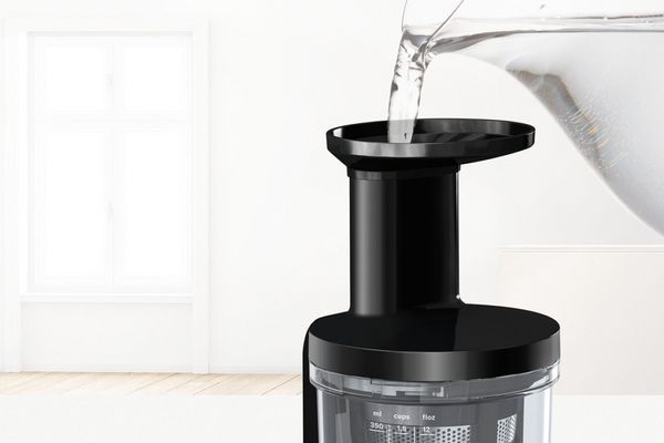 L'eau d'une jarre est introduite dans le Slow Juicer Bosch pour le nettoyer.