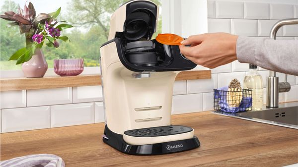 A person placing the service disk into the TASSIMO machine.