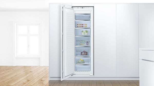 Frigorifero da libero posizionamento e frigorifero da incasso con le porte aperte in una cucina moderna.