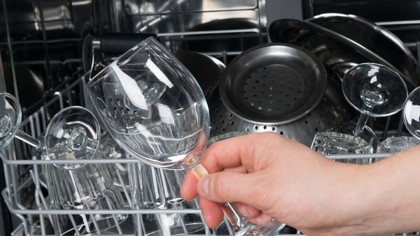 Person removing clean wine glass from dishwasher