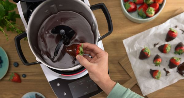 Le Cookit est rempli de chocolat fondu et une fraise est plongée dedans. 