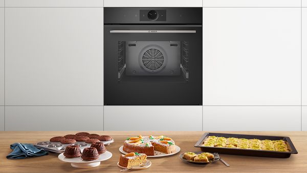 Ein Bosch Backofen als Einbaugerät in eine Küchenzeile integriert - auf der Küchenarbeitsplatte stehen verschiedene Kuchen.