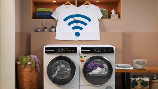 Zwei Geräte – eine Serie 8 Waschmaschine und ein Serie 8-Wärmepumpentrockner – stehen nebeneinander in einem Raum. Zwei weisse T-Shirts hängen nebeneinander über den Geräten, jeweils mit dem WLAN-Symbol bedruckt.