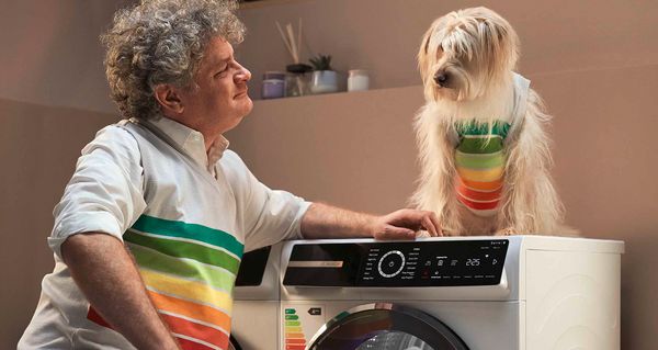 Ein energieeffizienter „Bosch Serie 8“-Wärmepumpentrockner der Energieeffizienzklasse A+++ steht auf einer Waschmaschine. Eine Socke hängt aus einem Wäschekorb daneben.