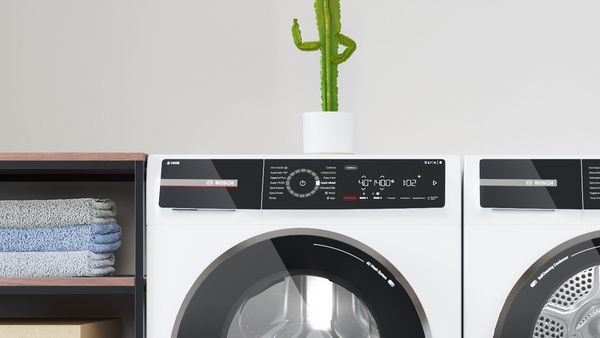 Közelkép a Series 8-as mosógép érintőkijelzőjéről. Egy kis zöld kaktusz áll a mosógép tetején.