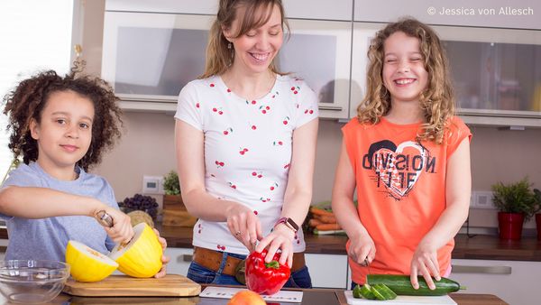 Kinder helfen Frau beim Zubereiten eines gesunden Gerichts.