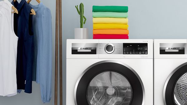 Una pila di vestiti colorati piegati sopra una lavatrice.