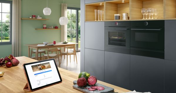 Tablet op een kookeiland met de Home Connect app open en Bosch huishoudapparaten in de achtergrond.
