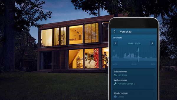 Im Hintergrund ein Haus in der Abenddämmerung und im Vordergund ein Smartphone mit Informationen über die Beleuchtung im Haus.