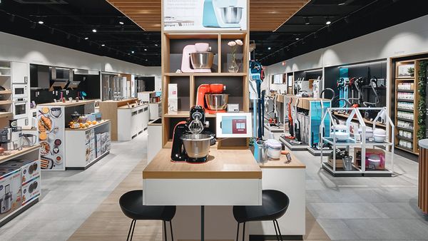 Hell beleuchtetes Interior des Bosch Showrooms mit Haushaltsgeräten und mittiger Sitzgelegenheit.