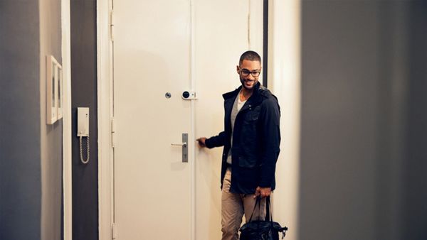 Ein Mann der seine Wohnung betritt. An der Türe ist ein Smart Home Gerät angebracht.