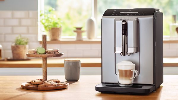 سلسلة 2 آلة قهوة VeroCafe مع كابتشينو على سطح المطبخ بجوار موقف البسكويت. 