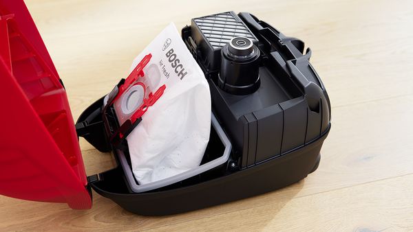 An open Bosch vacuum reveals the bag inside.
