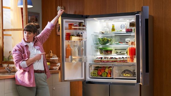 Person pointing to fridge with double doors open showing inside contents