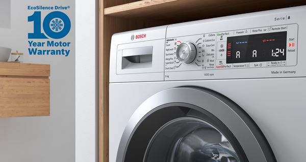 Free-standing Bosch washing machine with folded laundry on top. 10-year warranty icon at the left symbolises the free extended warranty on the motor.