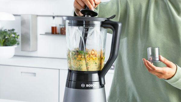 Woman filling VitaPower blender with vegetables.