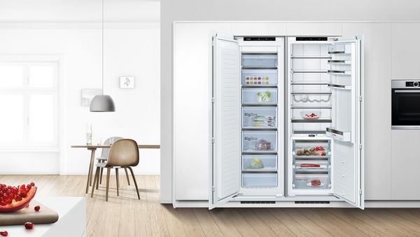 Ένας ανοιχτός εντοιχιζόμενος καταψύκτης δίπλα σε ένα ανοιχτό εντοιχιζόμενο ψυγείο.