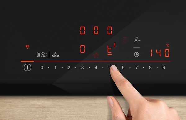 Ett finger väljer inställningar på en induktionshälls digitala kontrollpanel.