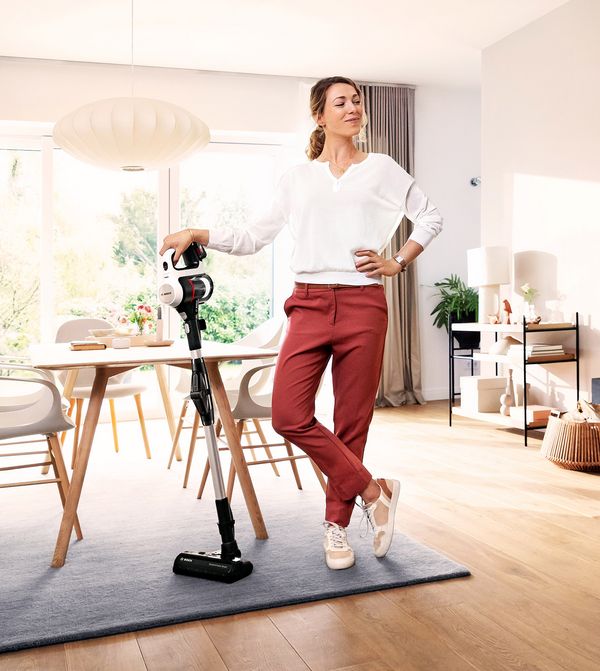 Person standing in living space with cordless vacuum cleaner