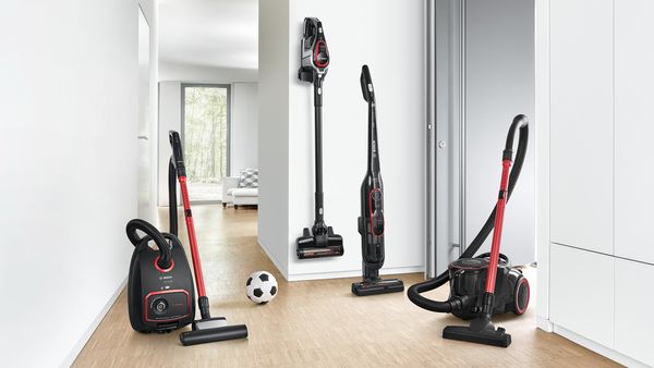 Different ProPower vaccums stand in a bright, white hallway with a football between them.