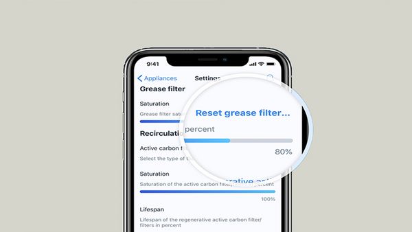 Pohled zblízka na displej chytrého telefonu zobrazující rozhraní aplikace s možností resetovat tukový filtr.