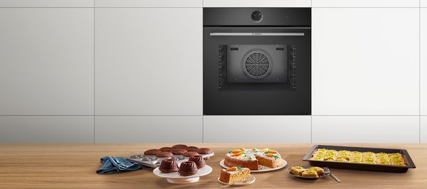 Wyspa kuchenna ze świeżymi wypiekami i piekarnikiem w tle.