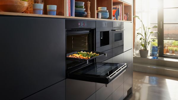 Bosch oven open with a tray of cooked vegetables.