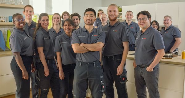A group of Bosch Service Technicians standing in a kitchen, all facing forward.