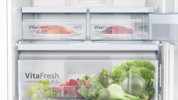 L'intérieur du réfrigérateur avec des produits frais, y compris les fruits, les légumes et les emballages de viande.
