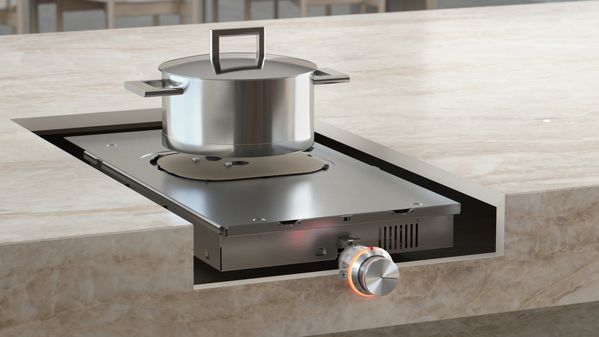 A kitchen island cutaway that reveals the unseen induction cooktop mechanism underneath