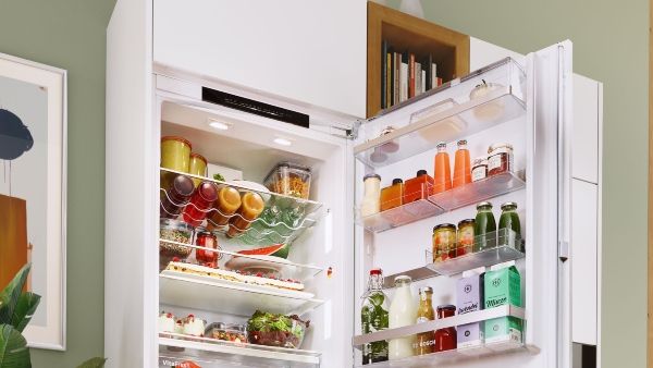 Fridge door open with lights showing different food and drink inside