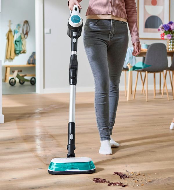 A person vacuuming and mopping with a Bosch Unlimited 7 Aqua vacuum and mop