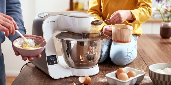 A person uses the blender attachment of the stand mixer to make a smoothie.