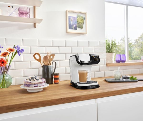 Tassimo coffee machine next to a cake plate in a kitchen environment 