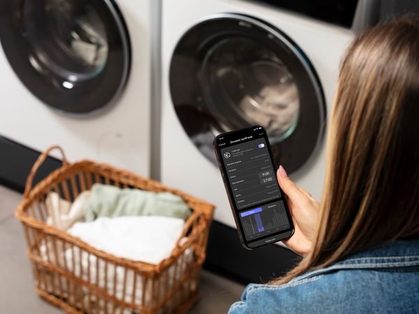 woman with phone connecting to washingmachine